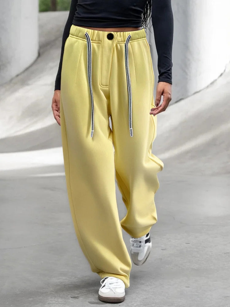 allvariants::Person wearing yellow sweatpants with zippers on a gray surface