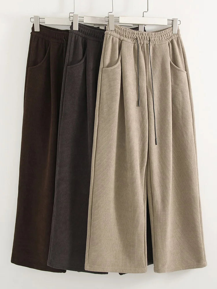 allvariants:: Two pairs of wide-leg pants, one black and one beige, hanging on a rack against a white background.