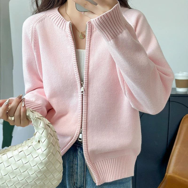 allvariants:: Person wearing a pink zip-up sweater holding a beige handbag indoors.