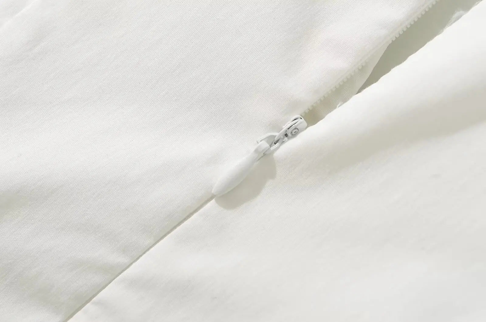 white::Close-up of a white zipper on a white fabric background