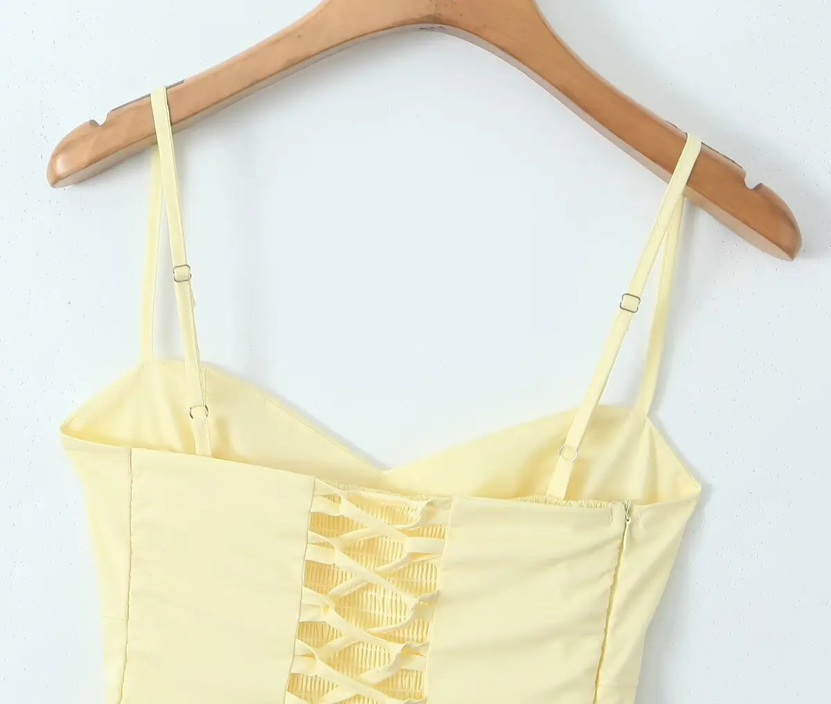 allvariant::Yellow crop top with a geometric pattern on a wooden hanger against a white background