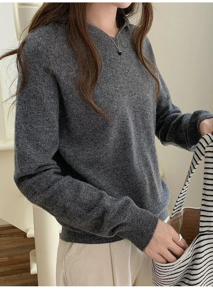 Dark Grey:: Person wearing a gray sweater holding a striped bag indoors.