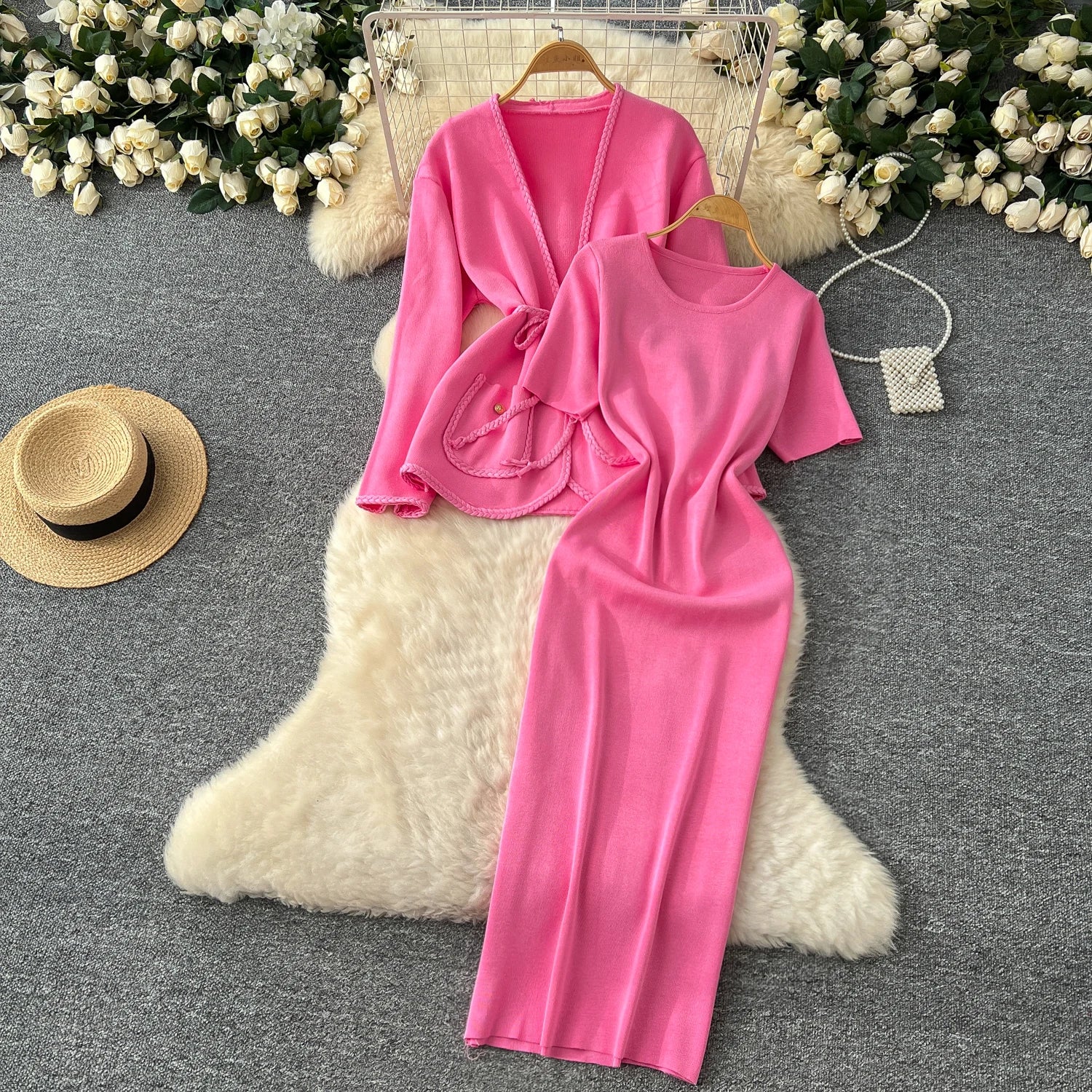 allvariants:: Pink outfit with a top and pants on hangers against a decorative background with flowers and a hat.