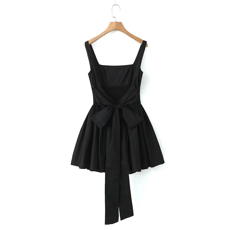 Black::Black dress with a bow detail on a hanger against a white background