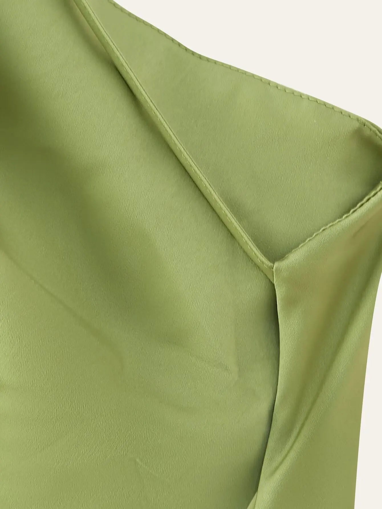 Green::Close-up of a green fabric with a V-neckline on a light gray background